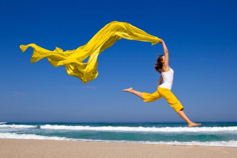 Девушка на пляже с желтой развевающейся тканью