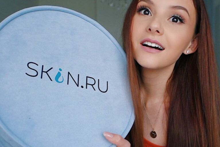 блогер Нюта держит круглую голубую коробку с логотипом Skin.ru