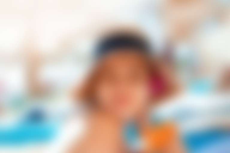 Девушка в шляпе на фоне пляжа с полосками солнцезащитного крема под глазами