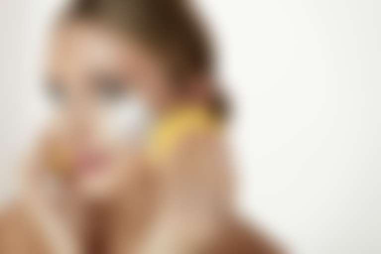 Девушка с мыльной пеной на щеках держит желтый спонжик