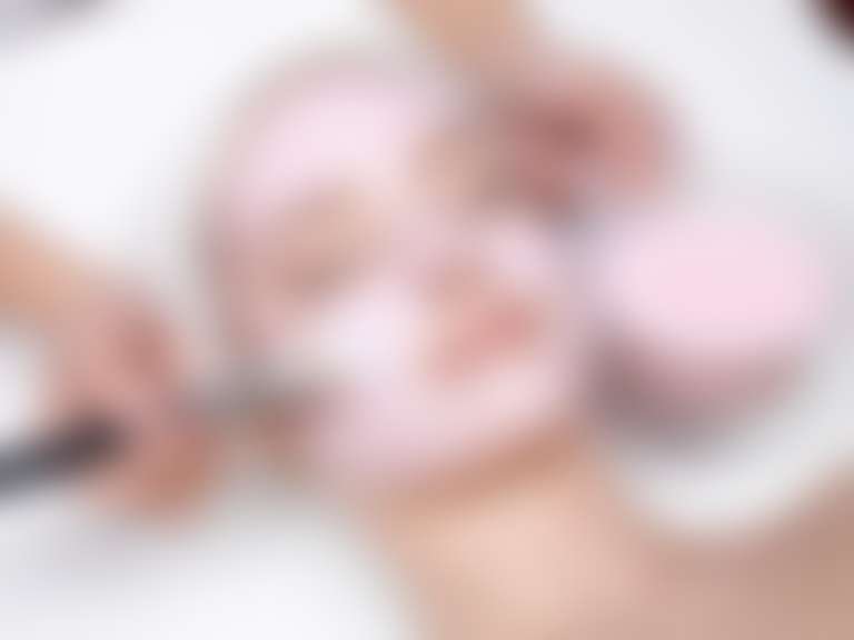 Косметолог наносит на лицо девушки маску для сухой кожи