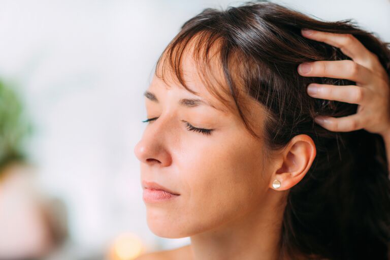девушка брюнетка делает массаж головы для роста волос