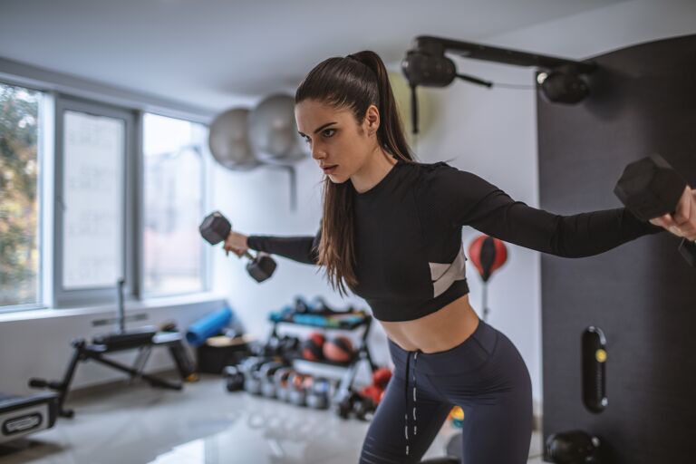Девушка в фитнес клубе делать комплекс упражнений на плечи.
