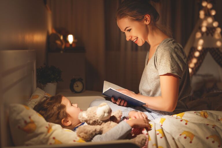 Мама перед сном читает малышу книгу.