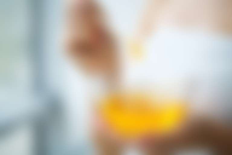 девушка в белом полотенце смешивает в стеклянной миске жидкий парафин с медом
