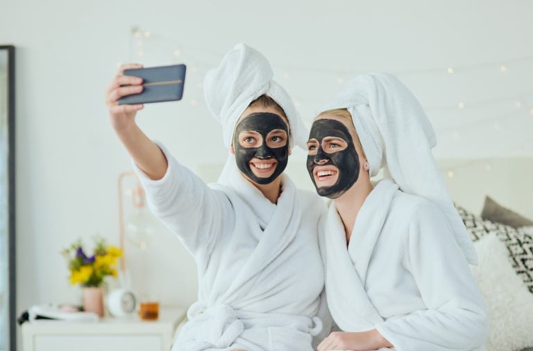 две девушки с черными косметическими масками на лице делают селфи