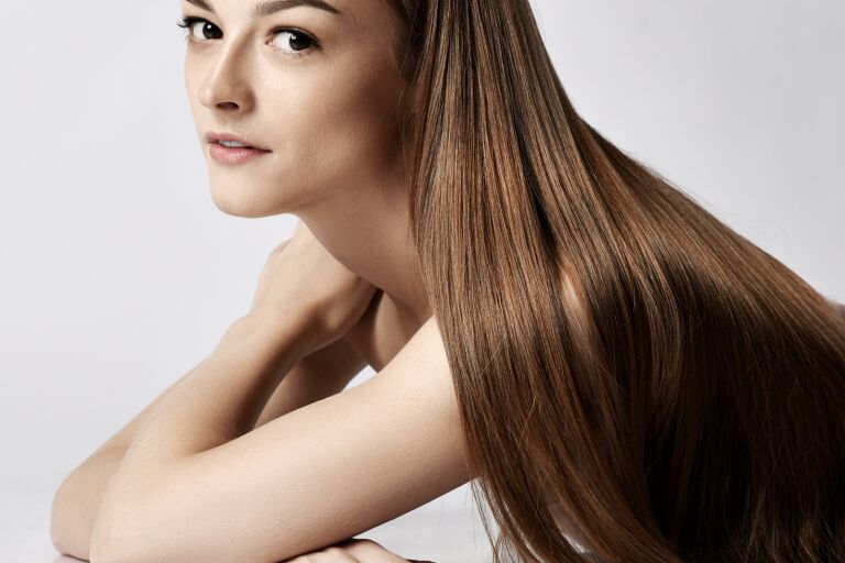 Русая девушка с очень длинными гладкими волосами после процедуры выпрямления волос