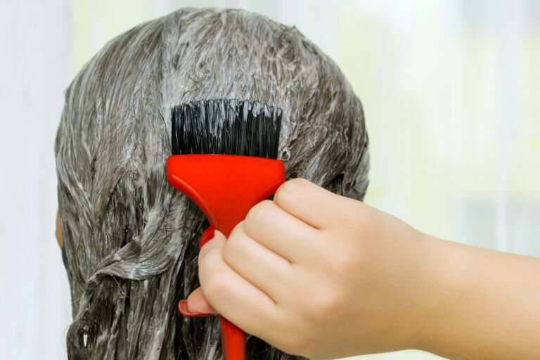 Девушка наносит на волосы восстанавливающую маску для волос