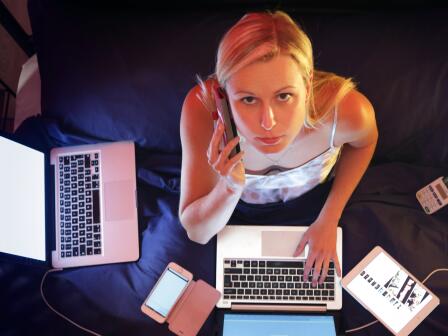 Девушка работает ночью в окружении компьютеров и смартфонов