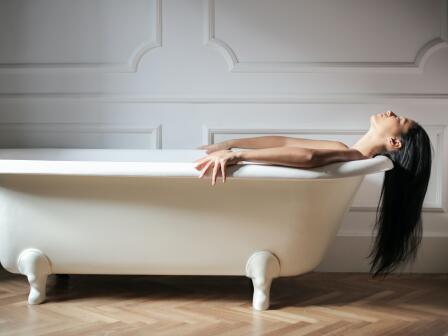 Девушка с длинными темными волосами в белой ванне